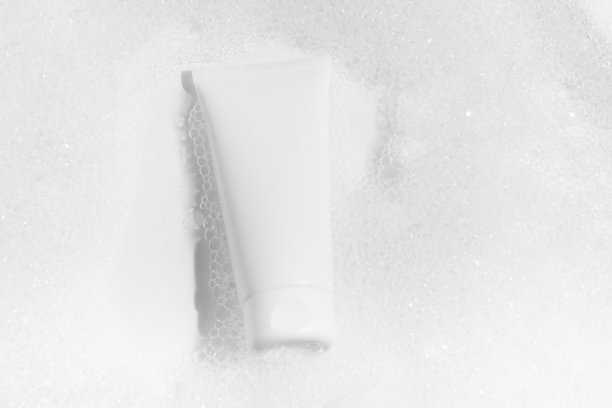 白色的模型一管奶油在水中与泡沫在白色的背景。概念的洗涤凝胶，保湿霜，化妆品美容和自我护理。图片为您的设计图片下载