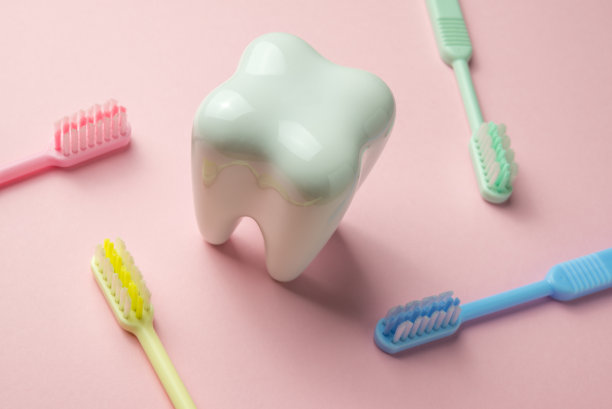 白色的牙齿和粉红色背景的彩色牙刷。图片下载