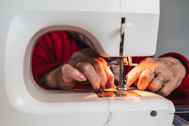 女裁缝在缝纫机的针下手工缝制衣服的细节图片下载