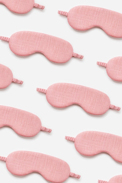粉色睡眠面罩上的最小图案。女性眼罩为最佳睡眠者，旅行，舒适休息。睡个好觉。创意唯美的俯视图照片，平铺图片下载