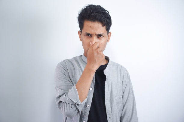 厌恶的人的肖像用手指捏鼻子，双手厌恶地看着有什么东西发臭难闻的情况孤立在灰色的墙壁背景。人的面部表情、肢体语言反应图片下载