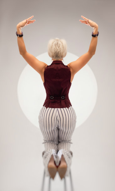 一个穿着西装的性感女孩坐在浅色背景的酒吧凳子上的工作室照片图片下载