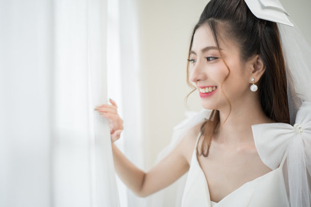 美丽的亚洲新娘与时尚的婚礼发型和化妆。年轻美丽的新娘的肖像在白色的房间里拍摄的婚礼工作室。图片下载