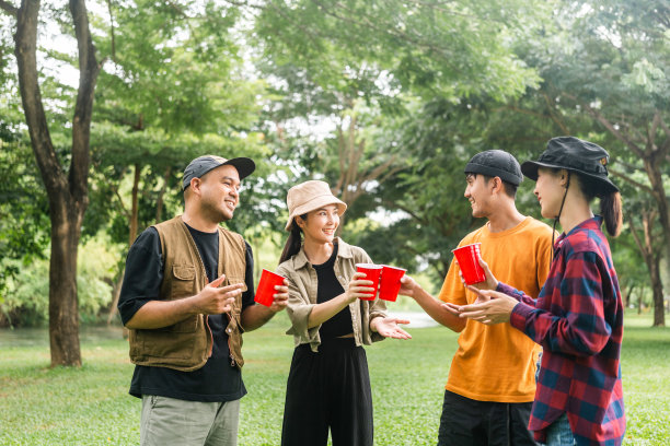 干杯!一群亚洲人朋友在大自然中露营，用软饮料和啤酒举杯祝酒。户外聚会在露营地自然森林背景在假日周末假期图片下载