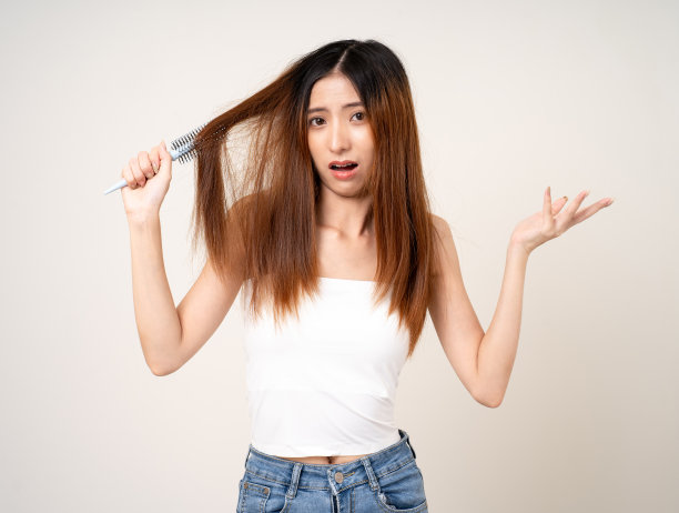 年轻的亚洲女性有头发问题，头发薄，受损，干燥，容易脱落，不健康，必须剪掉。站在孤立的白色背景上图片下载