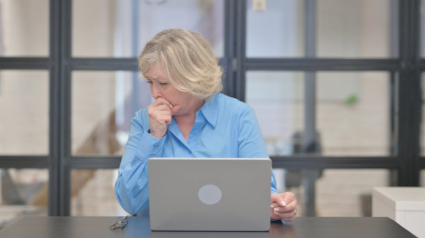 咳嗽的老商人在笔记本电脑上打字图片下载