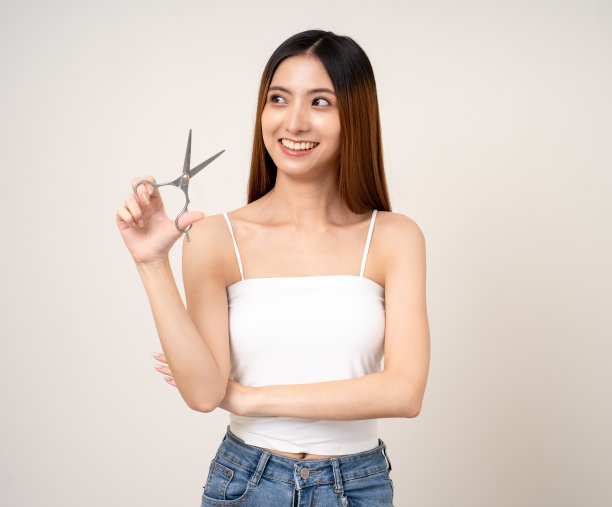 一个长头发的漂亮女人正在考虑用剪刀剪什么发型，或者去美容院。图片下载