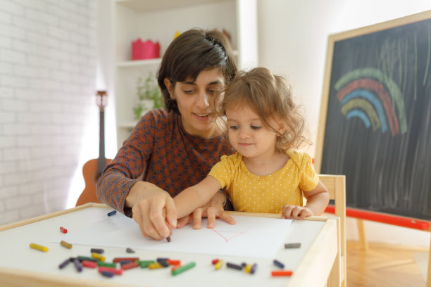 母亲和女儿坐在桌子上画画。图片下载
