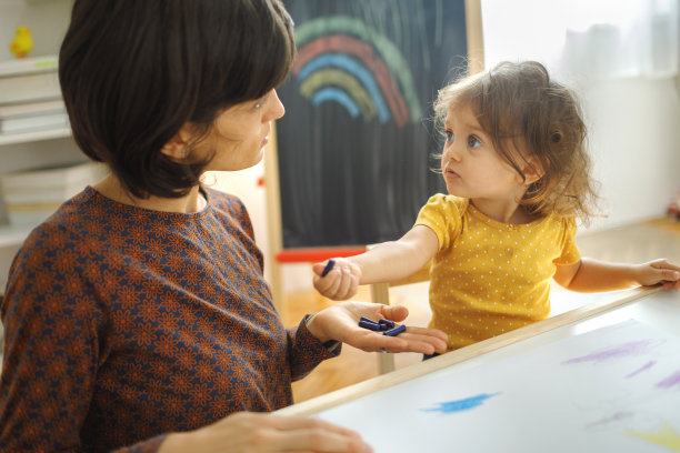 母亲和女儿坐在桌子上画画。图片下载