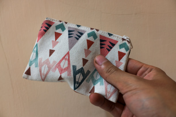 手里拿着白色的奶油色背景口袋钱包。图片下载