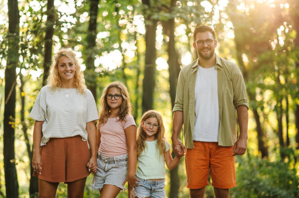一家人在森林里手牵着手，对着镜头微笑的照片图片下载