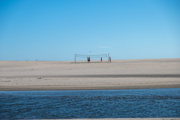 人们在沙滩上打沙滩排球的日落照片。暑假概念图片下载