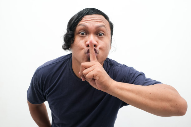 一名亚洲男子的特写照片，食指伸在嘴前。印度尼西亚人的肖像在孤立的白色背景上。沉默的手势，保密的手势，不要制造噪音，不要说话图片下载