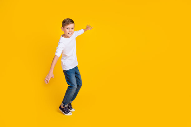开朗积极的孩子穿着白衬衫有乐趣飞行空空间孤立的黄色背景的全长照片图片下载