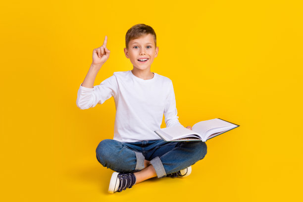 兴奋时髦的男孩穿着白衬衫看书指着空白的空间孤立的黄色背景的全长照片图片下载