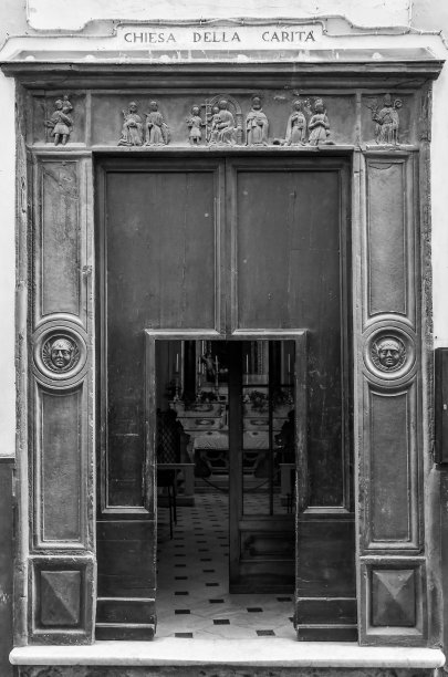 黑白照片。慈善教堂的石板门，14世纪由船主建造，位于意大利利古里亚萨沃纳著名度假胜地阿拉西奥的主要小巷图片下载