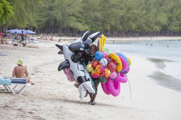 卖充气玩具和游泳圈给游客的海滩小贩沿着毛里求斯岛的沙滩走图片下载