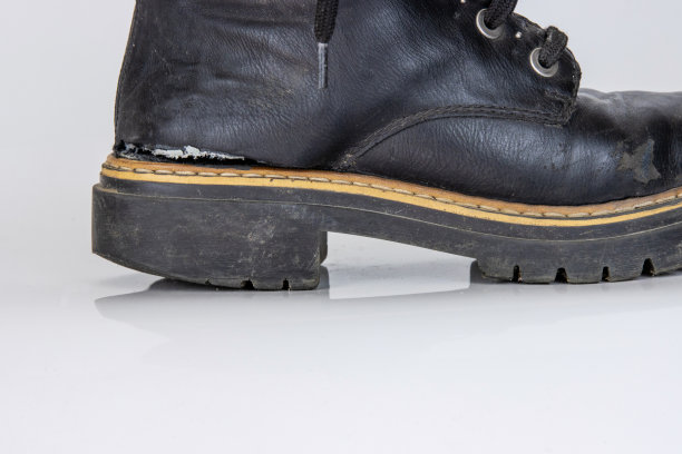 这是一双非常破旧的靴子的正面照片。旧的使用过的破碎的黑皮革蕾丝高靴。时髦的短靴。时尚的女士，男士，男女皆宜的垃圾靴子与鞋带。隔离在白色背景上图片下载
