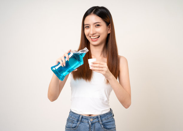 年轻的亚洲女性用漱口水来保持牙齿的健康。用漱口水清洁口腔，保持口腔健康。图片下载