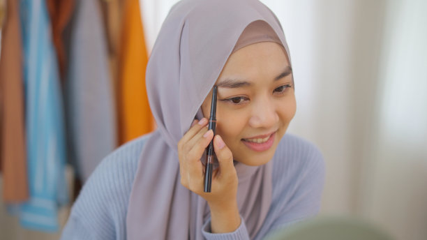 美丽的穆斯林女孩在社交媒体平台上直播故事自拍在家化妆示范。图片下载