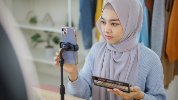 美丽的穆斯林女孩在社交媒体平台上直播故事自拍在家化妆示范。图片下载