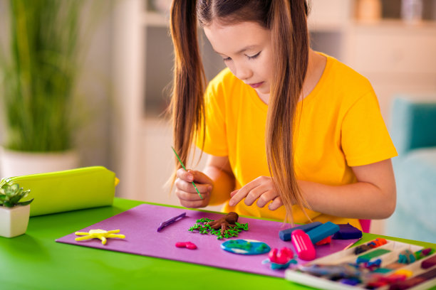 可爱漂亮的小女儿在家里室内制作手工橡皮泥人偶教育的照片图片下载