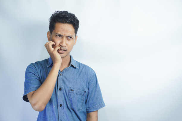 哦。悲伤恐怖的家伙的特写照片恐怖的面部表情犯了大错误感到内疚看侧面空白咬嘴唇手指穿蓝色衬衫孤立的白色背景图片下载