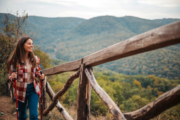 夕阳下站在户外的资深女性徒步旅行者的正面照片。图片下载