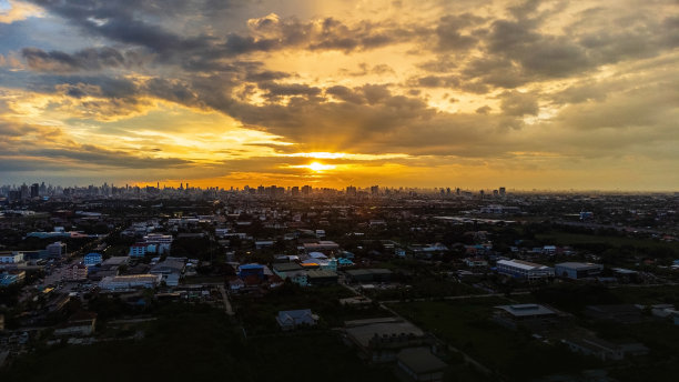 黄昏时城市鸟瞰图天空亮起了橙色。和明亮的紫色当太阳下山时，一个城市充满了高耸的摩天大楼和低矮的建筑在黄昏。图片下载