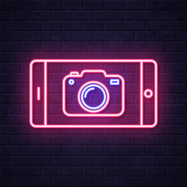带摄像头的智能手机。在砖墙背景上发光的霓虹灯图标图片下载