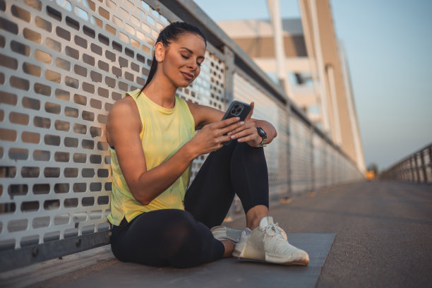 一名肌肉发达的年轻女子在户外运动后使用手机的照片图片下载