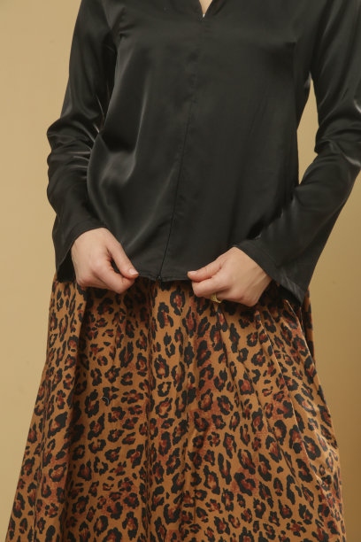 一系列的工作室照片的年轻女模特穿着黑色衬衫与动物印花中长裙。舒适优雅的日常时尚。图片下载