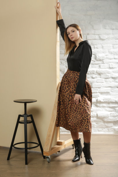 一系列的工作室照片的年轻女模特穿着黑色衬衫与动物印花中长裙。舒适优雅的日常时尚。图片下载