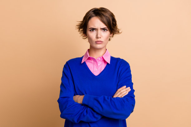 可爱的年轻女士的照片肖像交叉手臂皱眉烦恼穿着时髦的蓝色服装孤立的米色背景图片下载
