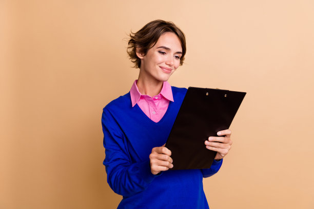 可爱的年轻女士的照片肖像拿着纸夹文件穿着时髦的蓝色服装孤立在米色背景图片下载
