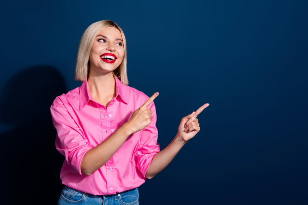 可爱的女人的照片，波波发型，红唇，穿着粉红色的衬衫，看着销售，在深蓝色的背景上孤立的空白空间图片下载