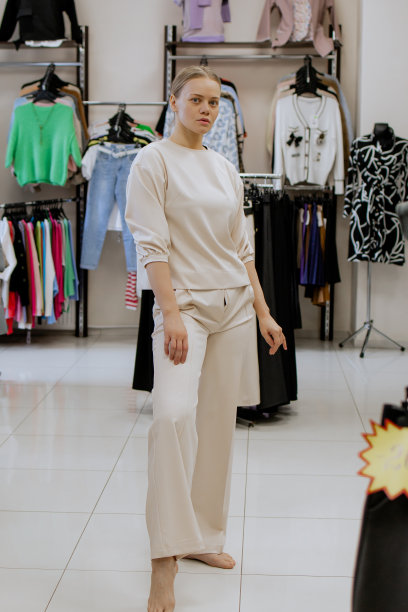 快乐的女人在更衣室里一边试穿衣服一边看着镜子里的自己，摆姿势，买休闲服装，在时尚女装店，在精品店。购物。图片下载