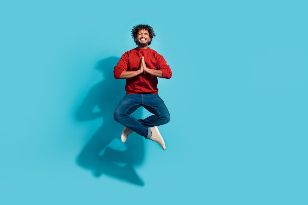 完整尺寸的照片，男子跳跃与合掌在莲花姿势恳求祈祷上帝的帮助，孤立的青色背景图片下载