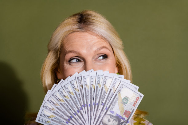 近距离照片的成熟年龄富有的妇女隐藏脸匿名扑克玩家持有许多钱孤立的卡其色背景图片下载