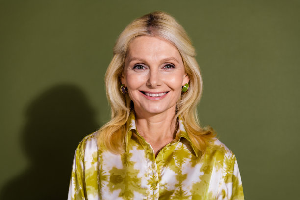 照片的华丽漂亮可爱的女人穿着时髦的衣服，手触摸脸健康的皮肤隔离在卡其色的背景。图片下载