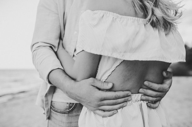 男女拥抱在沙滩上，享受夏日。男人和女人在沙滩上拥抱。浪漫的情侣拥抱在一起。共度时光。手的特写。后视图。黑白照片图片下载