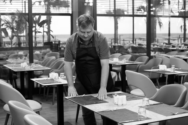 一个成年服务员在餐厅摆好桌子，黑白照片图片下载