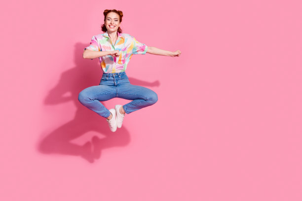 全身照片迷人的红头发迷人的模特跳穿休闲装拳头动作舞蹈孤立在粉红色的背景图片下载