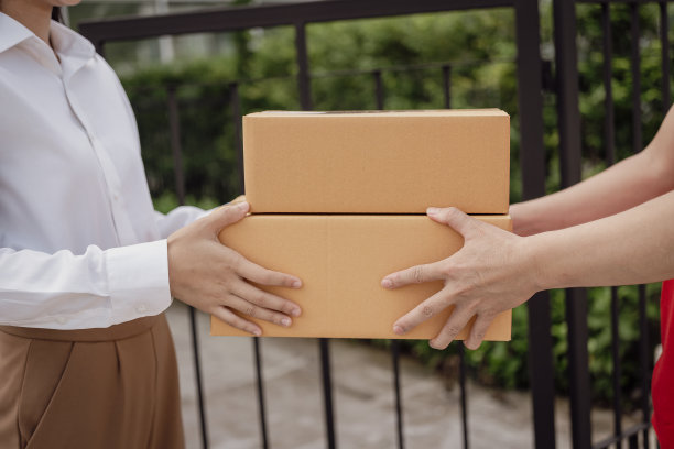 快递员、箱子和物流概念包裹或快递服务站在服务提供商或产品的前门，用于在线购买、运输或电子商务。特写照片图片下载