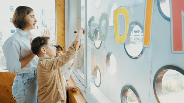 年轻漂亮的老师在美术课上教不同的学生绘画。博学。图片下载