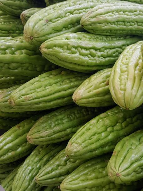 一张桌子上放着一堆绿色苦瓜的照片。图片下载