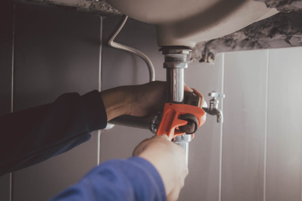 在浴室工作的水管工，管道维修服务，修理水管道泄漏，更换厨房水槽排水管图片下载