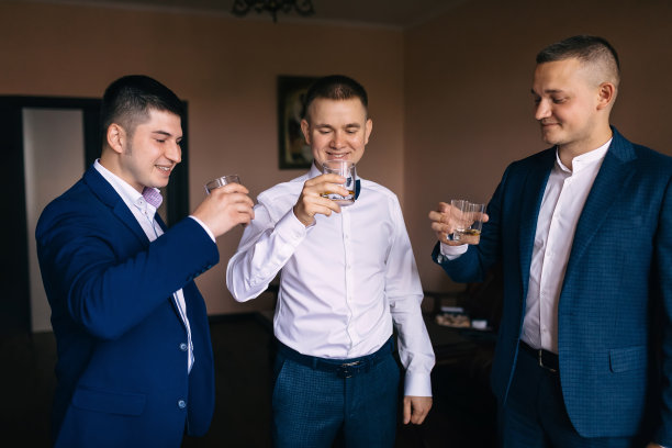 三个穿着帅气西装的男人微笑着喝着威士忌。图片下载