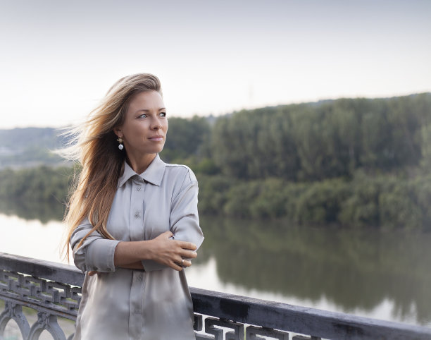 在河的背景上，一个穿着灰色裙子的美丽女孩的肖像图片下载