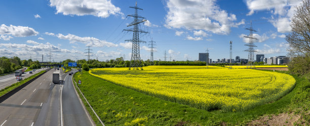 一条适度繁忙的德国高速公路全景照片，草地边缘，盛开的油菜地，架空的电线，散落的云和美丽的天气图片下载